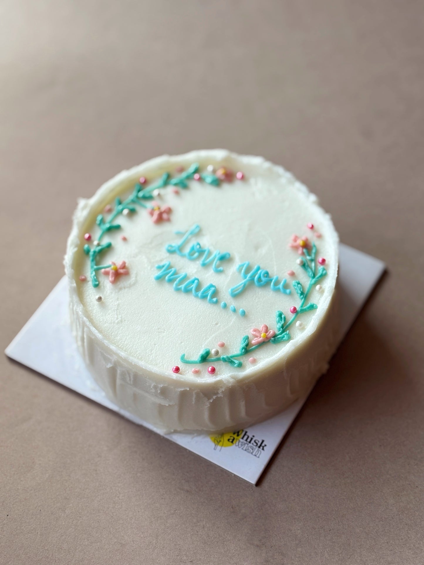 Whisk & Wish “Love you mom” floral chocolate berry bento cake with delicate pastel floral decorations, presented on a white cake board, highlighting a heartfelt handcrafted dessert for Mother’s Day or special occasions.